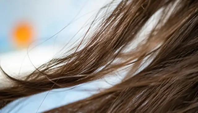 Close-up de fios de cabelo com texturas diferentes sendo observados sob luz natural
